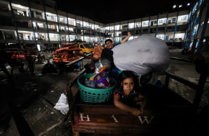 A family that was sheltering at a United Nations run school, return with their belongings to their home following the ceasefire [Mohammed Abed/AFP]