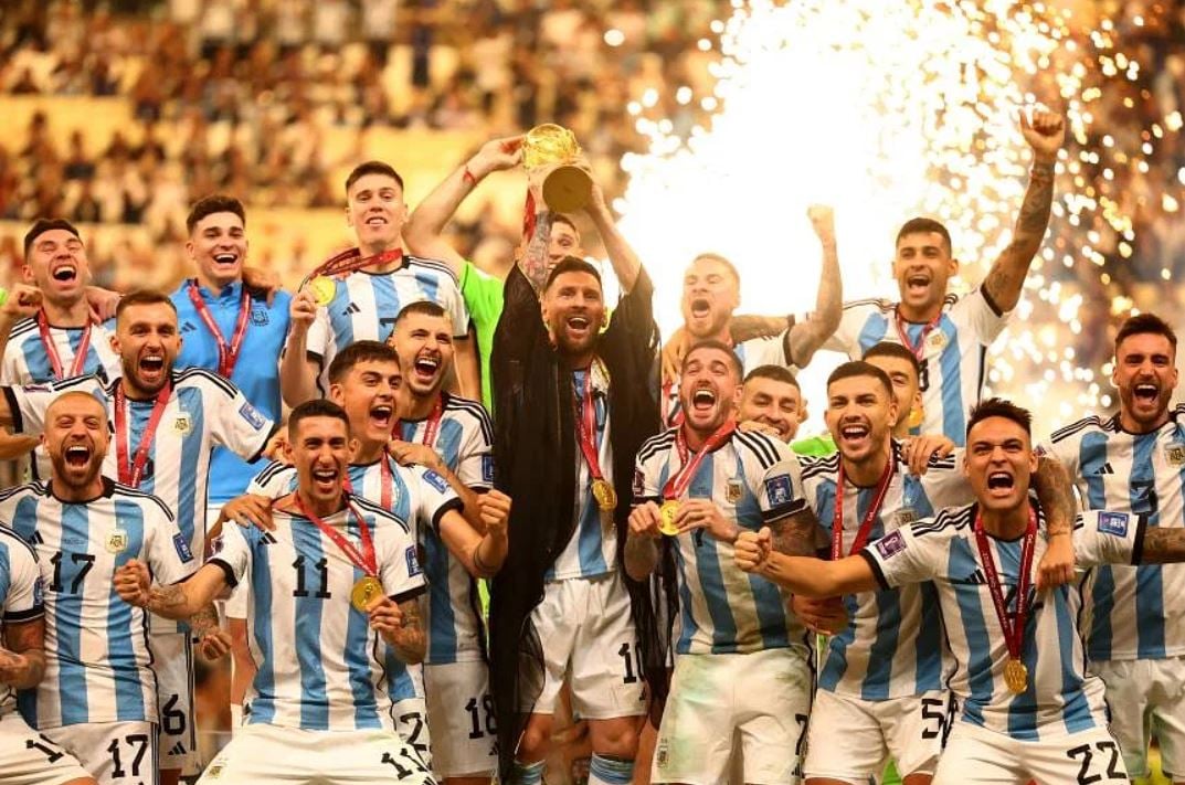 Argentina's Lionel Messi lifts the World Cup trophy alongside teammates as they celebrate their victory. (PHOTO: REUTERS)