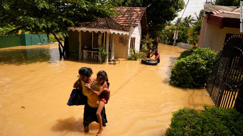 A woman and child wade through a flooded area in Kochchikade, Sri Lanka on November 10, 2021.