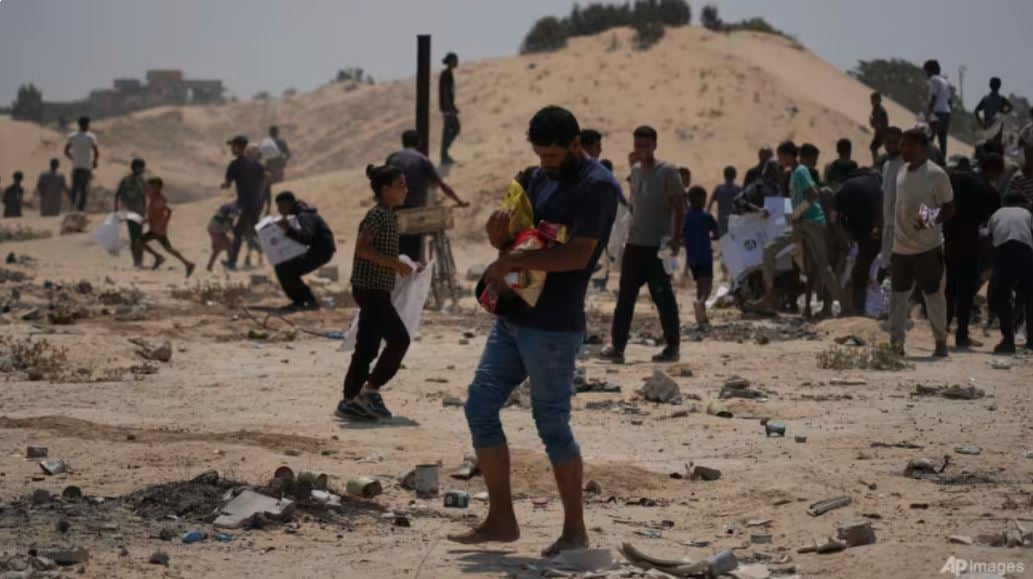 Palestinians collect humanitarian aid from the UAE after they were airdropped into Deir al-Balah, in central Gaza Strip, Saturday, Aug. 9, 2025. (AP Photo/Abdel Kareem Hana)