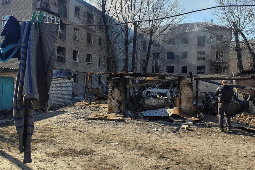 A man stands next to cars destroyed by shelling in Rubizhne, Luhansk.