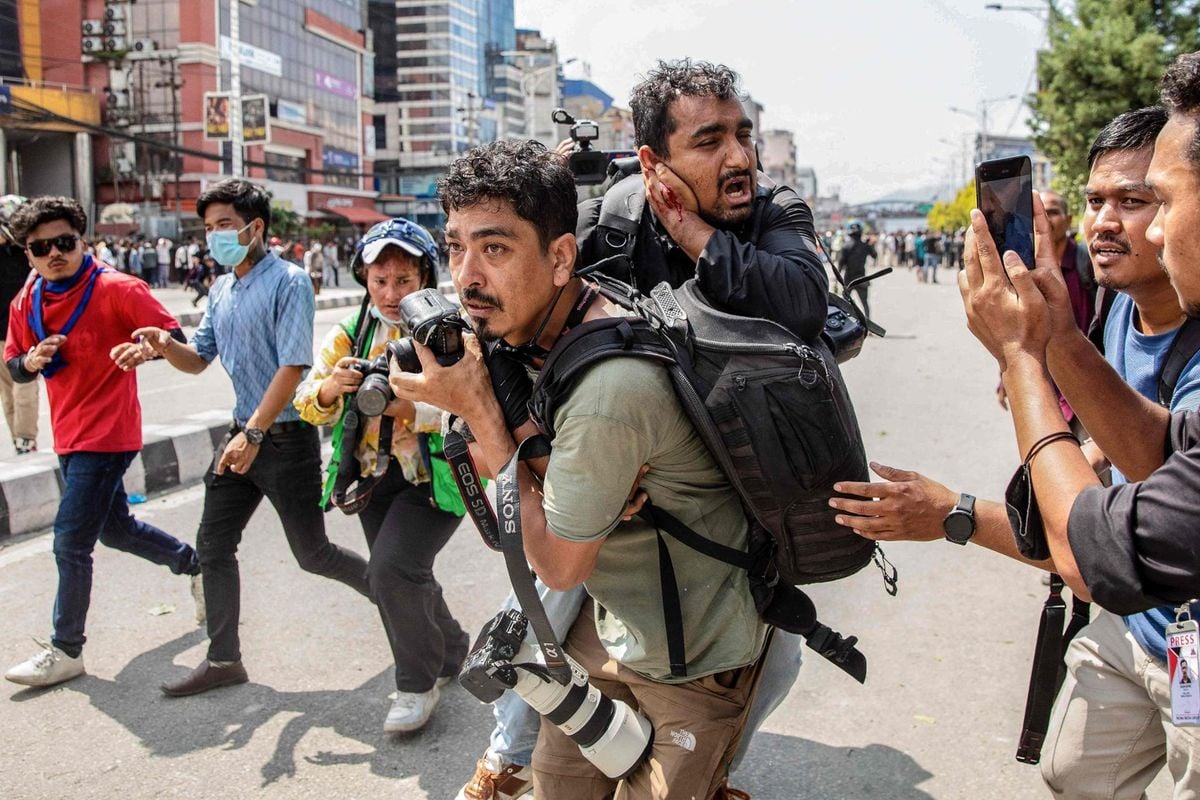 A photojournalist carries an injured colleague during protests in Kathmandu on Sept. 8. (AFP-Yonhap)