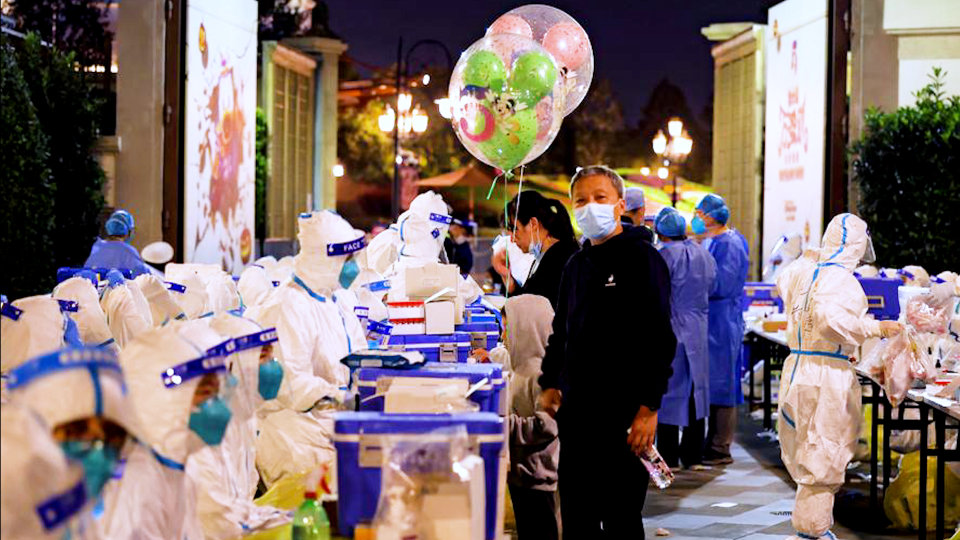 Medical personnel test visitors for the coronavirus at Disneyland in Shanghai on Sunday after a single COVID-19 case was detected at the park over the weekend.