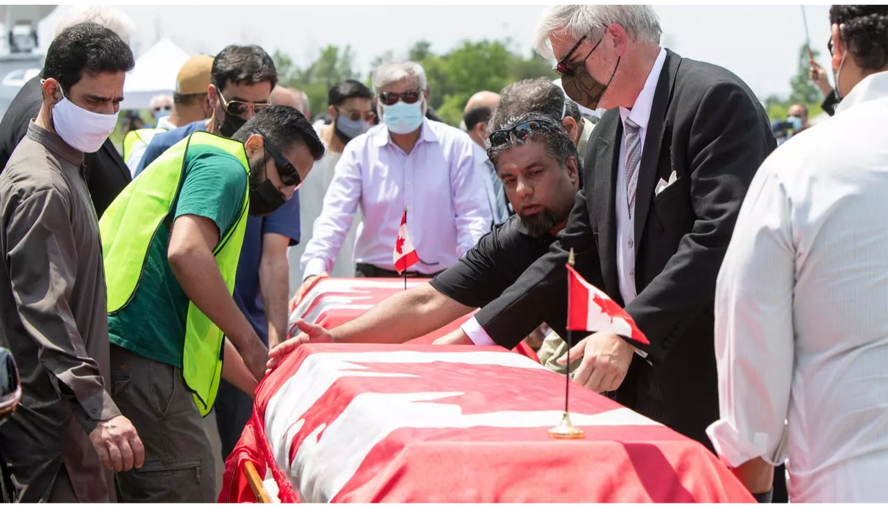 Pallbearers move the caskets of four members of the Afzaal family at the Islamic Centre of Southwest Ontario on June 12, 2021