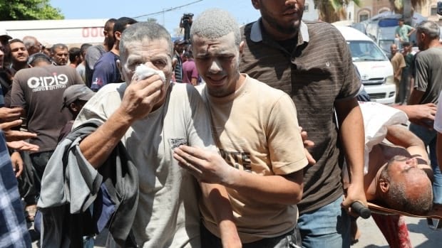 An injured Palestinian man covers his face as another walks with him at Al-Aqsa Martyrs Hospital, in aftermath of an Israeli attack on Saturday. (Reuters)