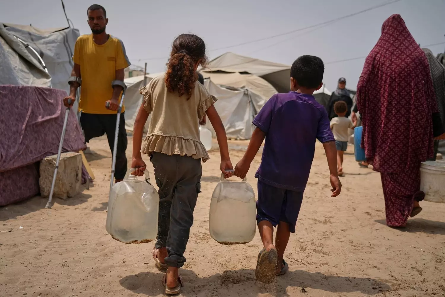 Palestinian children haul jerrycans of water collected from a distribution point in Gaza City, Aug. 12, 2025. (AP Photo/Jehad Alshrafi)