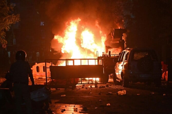 A firefighter stands near the burning vehicles set on fire following clashes at the Chitnavis Park Square area, in Nagpur on March 17, 2025. (AFP)