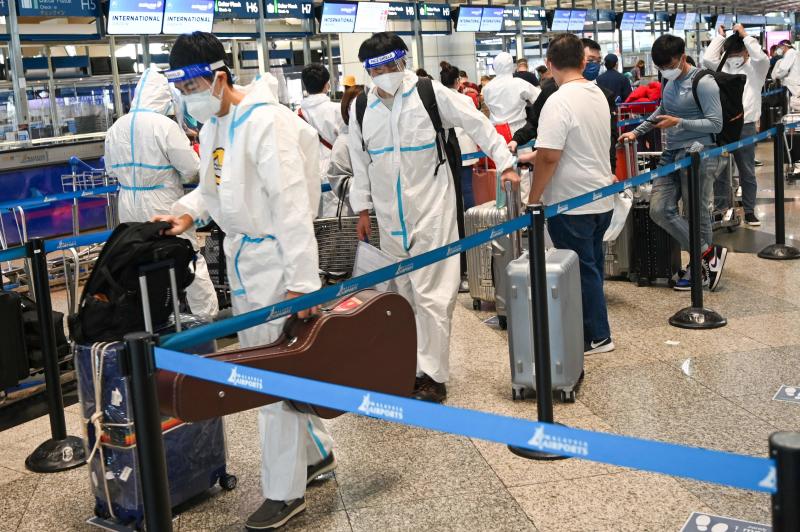 Passengers wearing PPE queue to check-in for their flight at the Kuala Lumpur International Airport.