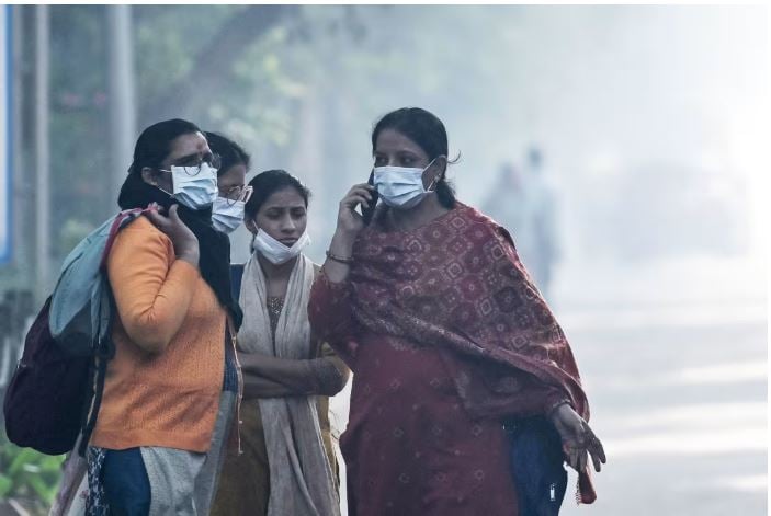 Women waiting to board a bus amid smoggy conditions in New Delhi. Photo: Arun Sankar / AFP via Getty Images