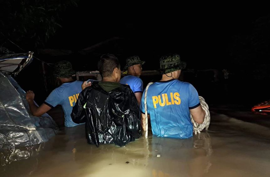Policemen wade through floods to rescue trapped residents in Upi, Maguindanao del Norte, Philippines.