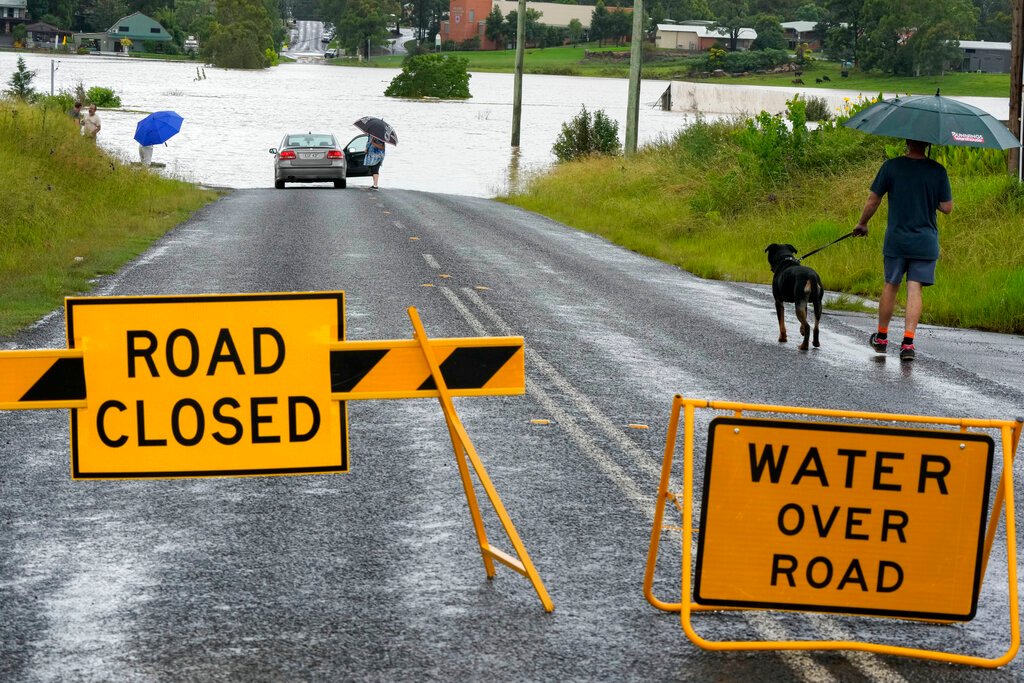 Residents look over a flooded road near Windsor on the outskirts of Sydney on March 3. (Photo: AP)