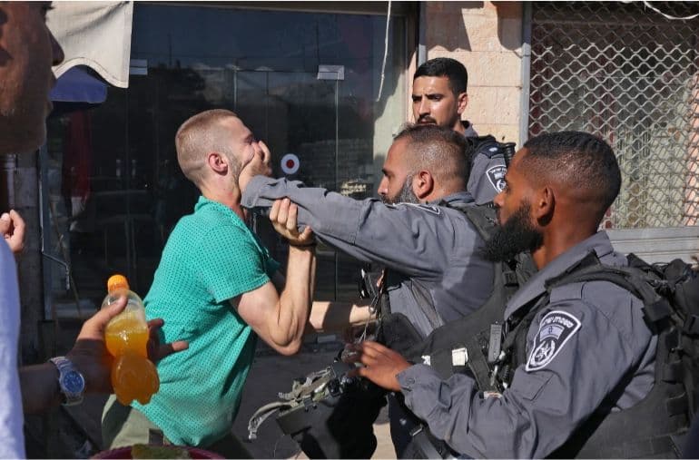 A member of the Israeli forces pushes away a Palestinian man in the Old City of occupied East Jerusalem, on June 15, 2021.