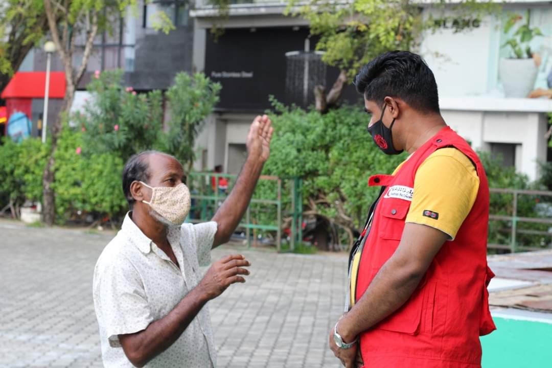 A volunteer speaking with a migrant worker, HPA has mandated to wear masks in all the residential islands. Photo: Maldivian Red Crescent/Social Media.