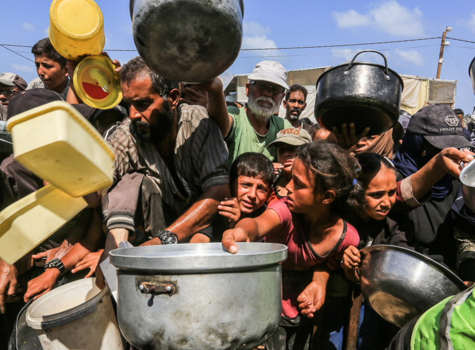 Palestinians, who are struggling to access food, wait in line to receive hot meals. Photograph: Anadolu/Getty Images