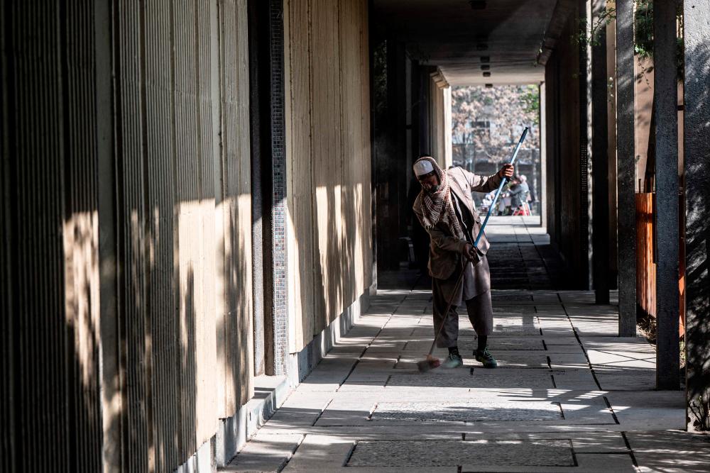 A worker cleans the corridor of Esteqlal High School in Kabul on March 21, 2023. (PHOTO: AFP)