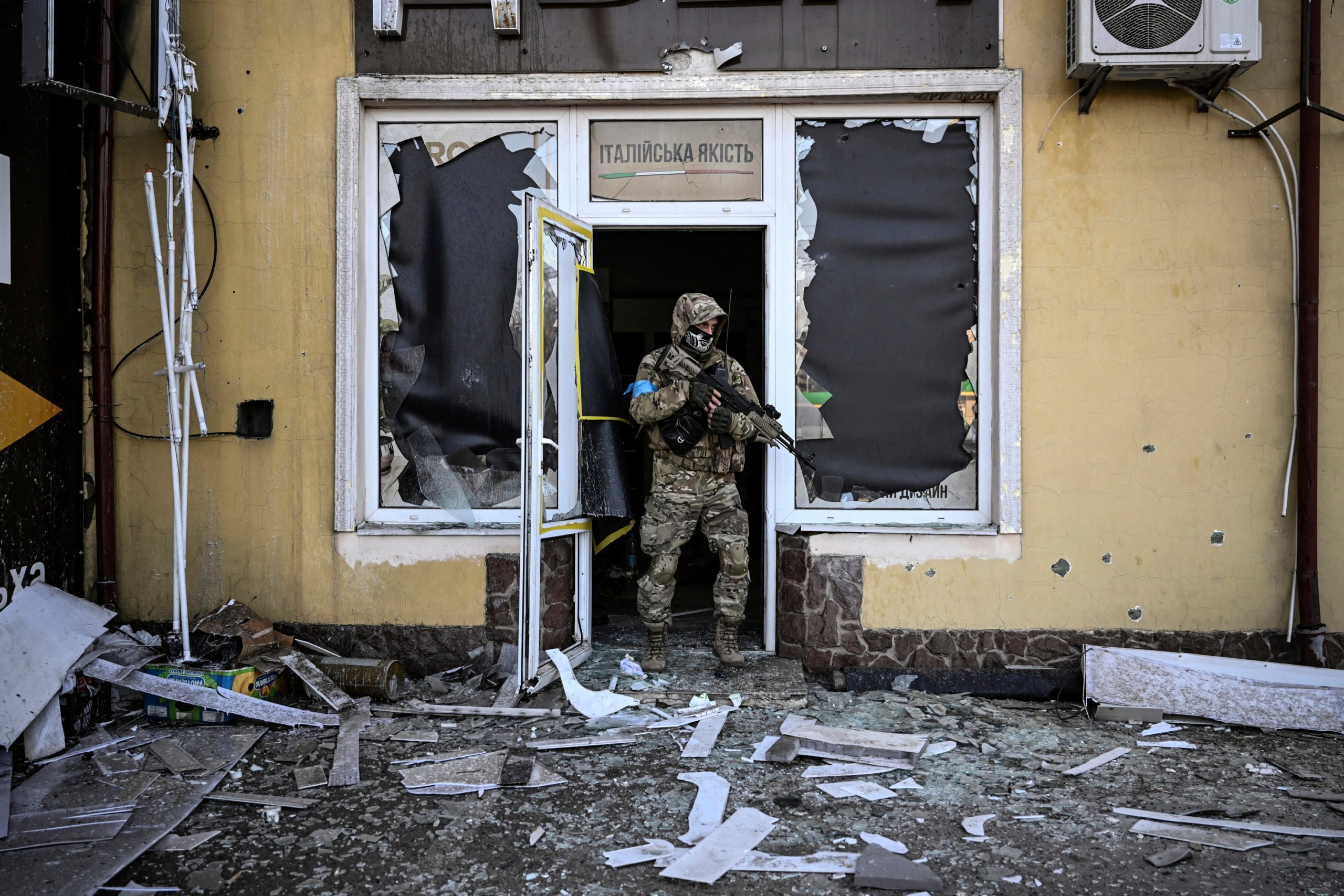 A Ukrainian serviceman exits a damaged building after shelling in Kyiv.