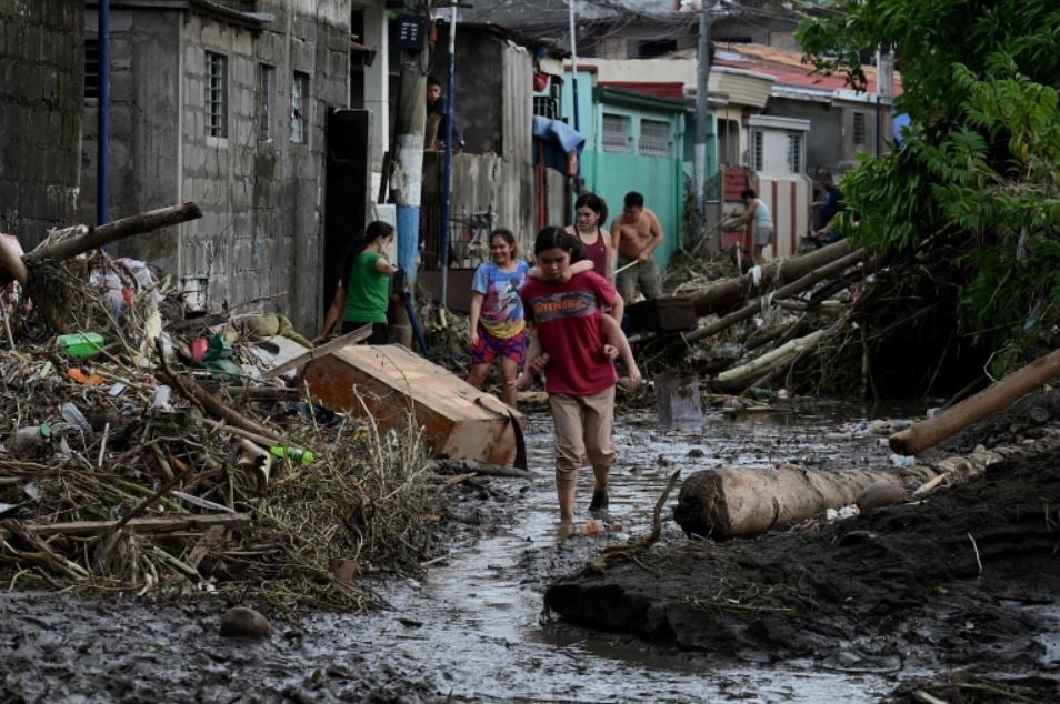 Residents began cleaning up their homes after streets were deluged in mud and flood waters [Jam Sta Rosa/AFP]